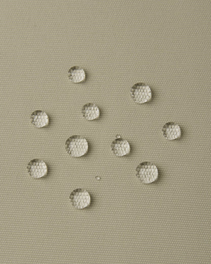 Macro close-up of water droplets actively beading and rolling off the earthy beige outer shell of the Reima Wingon kids' ski pants, visually highlighting the high-performance breathable and waterproof Reimatec technology.