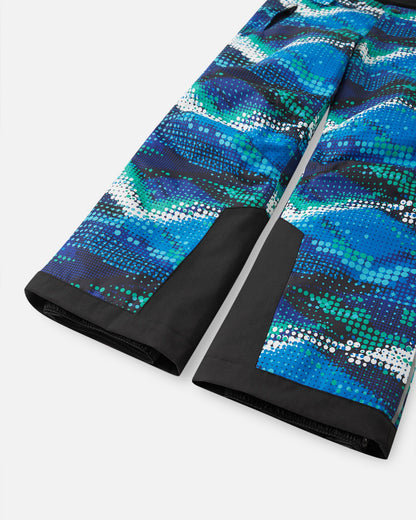 Detail view of the lower legs on the twilight blue Reima Wingon kids' ski pants, emphasizing the rugged black reinforced hems to protect against ski edges and the inner elastic snow locks designed to securely grip winter boots.